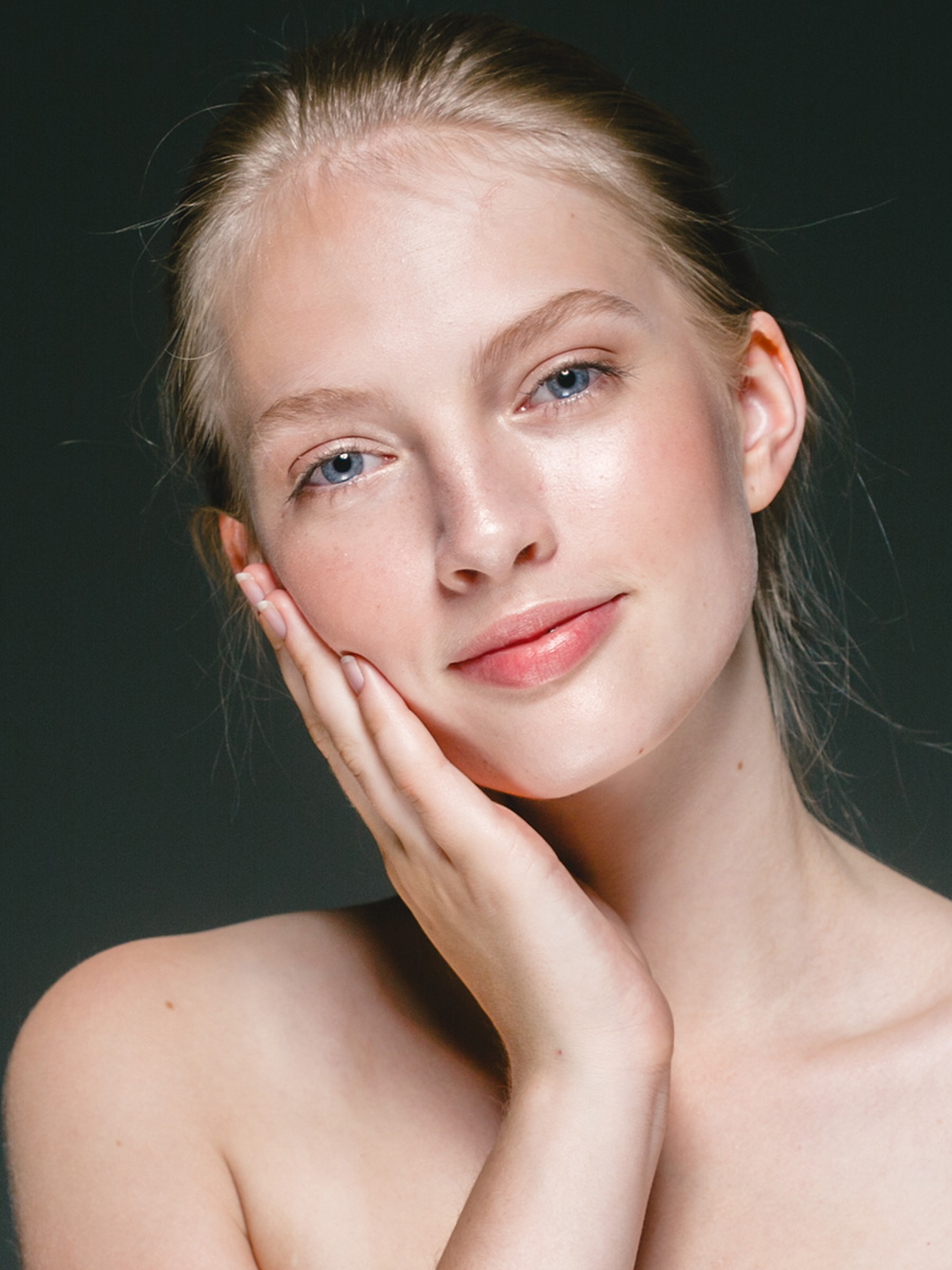 Young woman with smooth skin touching her face