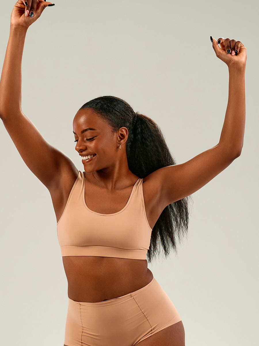 Woman in tan with her arms raised