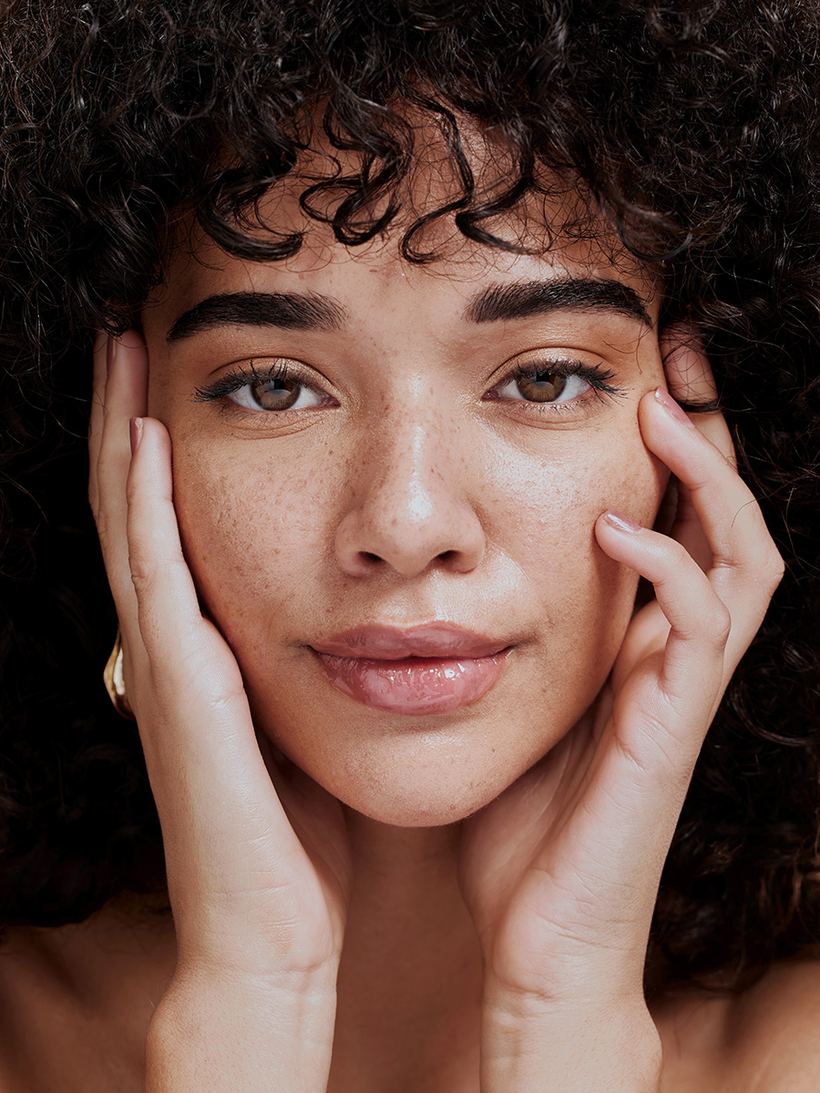 a young woman with freckles touching her face