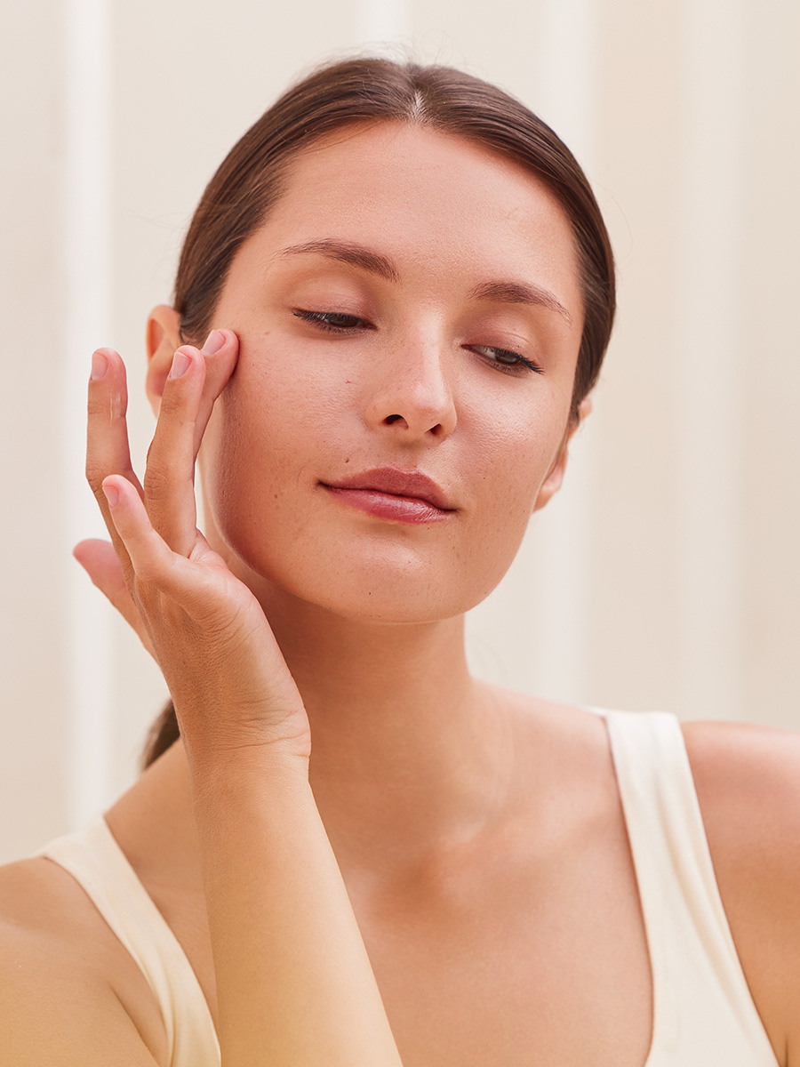 woman in a white shirt touching her face