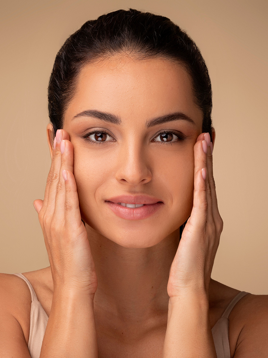Woman with dark hair touching her face